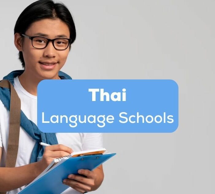 A Thai student with a bag writing on a paper behind the Thai language schools texts.