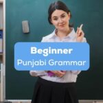 A pretty female teacher inside a classrom behind the beginner Punjabi grammar texts.