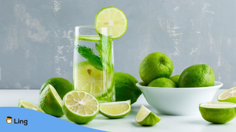 A photo of a lime juice with slices of lime around it.
