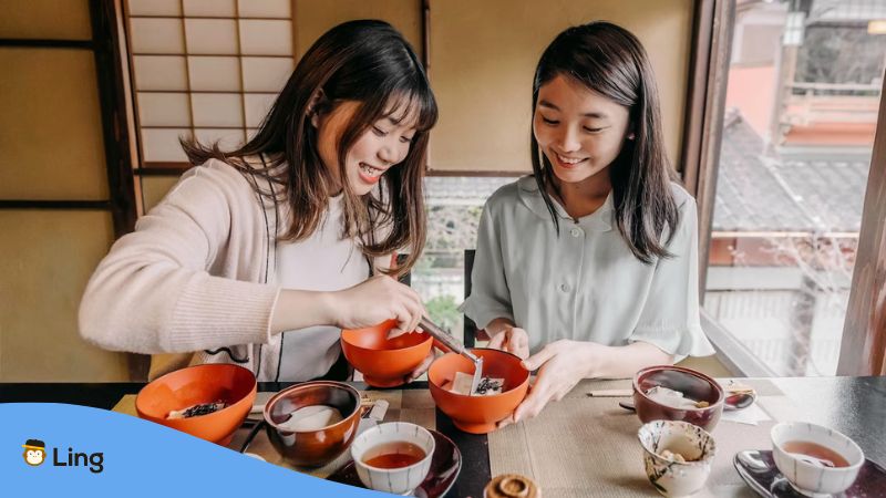 Two South Korean girls sharing food inside a small cozy restaurant.