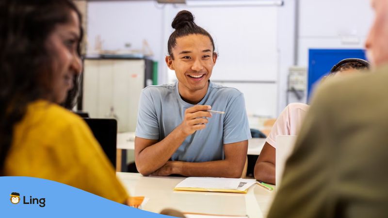 A smiling male with his intermediate grammar learners inside a classroom.