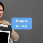 A happy female holding an iPad beside the nouns in Thai texts.