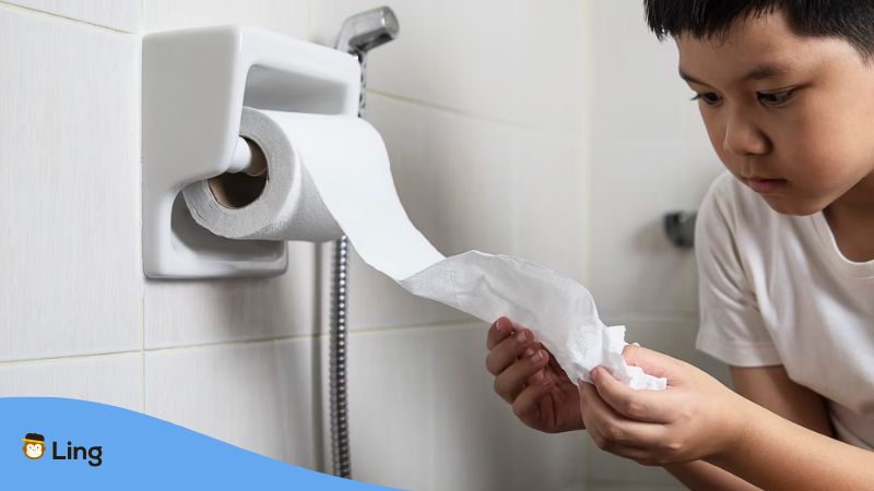 An Asian boy holding a tissue paper inside a restroom in the Philippines.