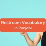 A man in a black sleeveless shirt and a towel on his head beside the restroom vocabulary in Punjabi texts.