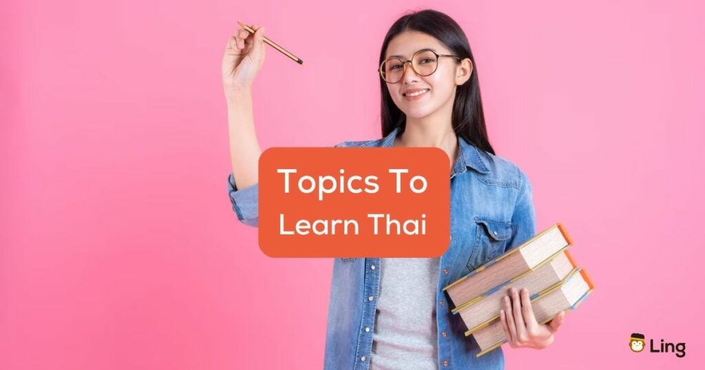 A pretty teenage female holding books in her arm and using pencil behind the topics to learn Thai texts.