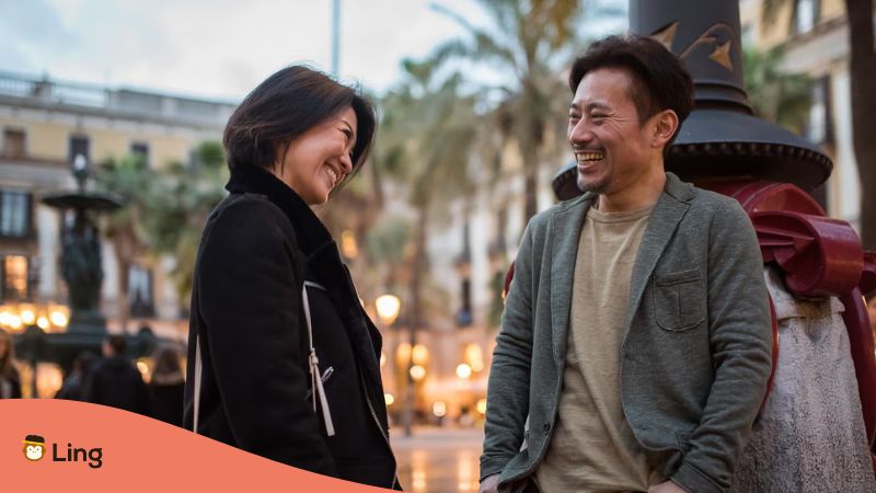 A photo of an Asian happy tourist couple talking in a square who knows topics to learn Thai.