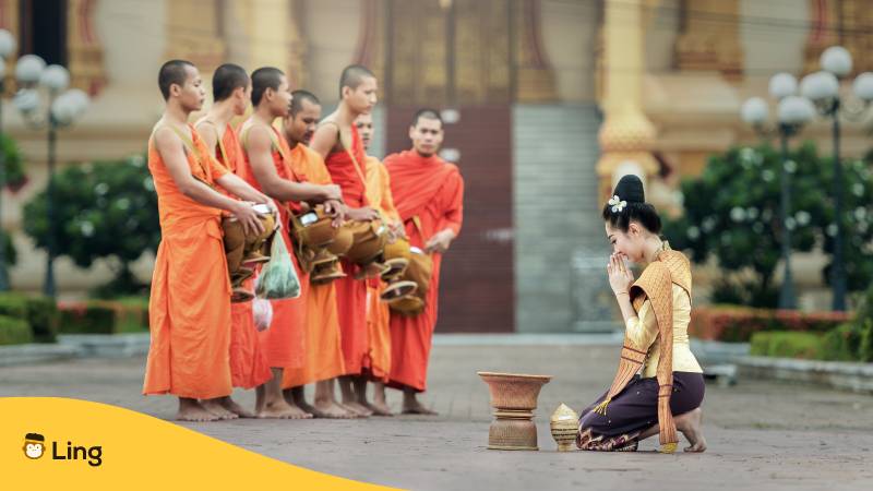 7 buddhistischen Mönche die ihrer Religion in Laos folgen. Die Mönche erhalten von kniender Frau Almosen