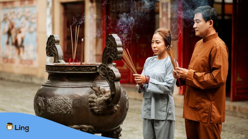 A photo of a man and a woman with incense outside a temple in Hong Kong.