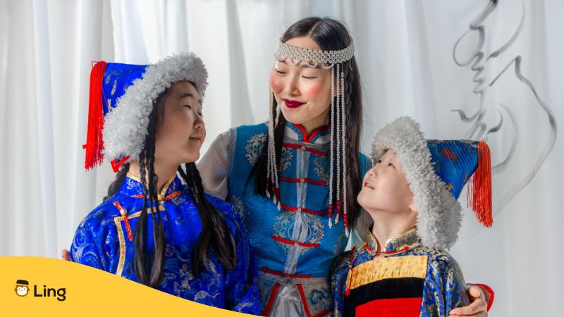 Mongolische Mutter mit zwei Kindern in traditioneller Tracht bringt ihnen bei, sich respektvoll zu bedanken