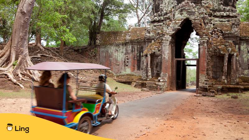 Tuktuk mit zwei Touristen fährt auf den Eingang von Angkor Wat in Kambodscha zu