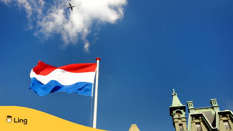 Niederländische Flagge weht vor einem Gebäude mit blauen Himmel