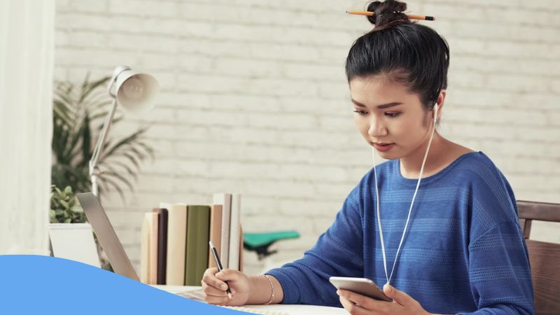 A photo of a female Korean language learner using her phone reading KoreanClass101 review.