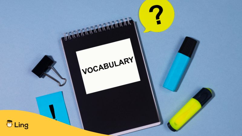black notebook with a vocabulary tag with highlighters, clip and paper on the side 