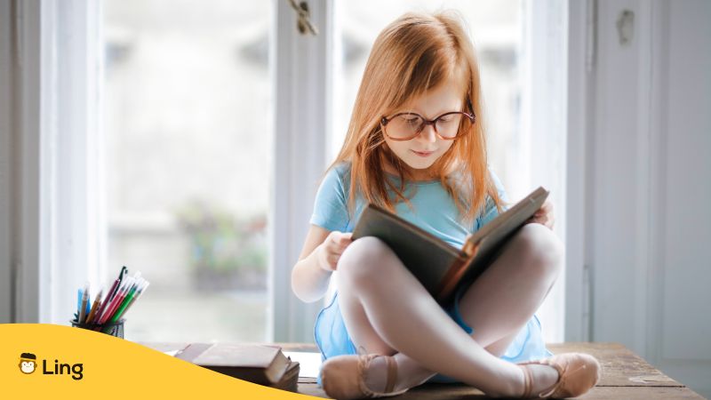 child wearing eyeglasses and ballet shoes reading a book