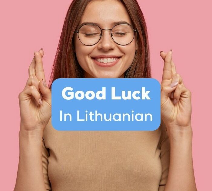 A photo of an excited girl with crossed fingers and closed eyes behind the Good Luck In Lithuanian texts.