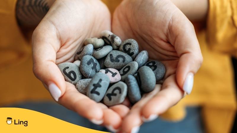 Niederländische Zahlen aus Ling-App zeigt Hände gefüllt mit Zahlen aus Steinen