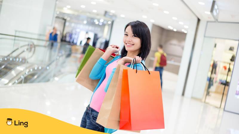 Frau hält mehrere Einkaufstüten in der Hand und freut sich die wichtigsten Wörter zum Einkaufen nutzen zu können
