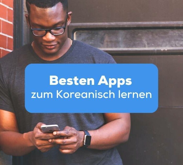 Mann lehnt an einer Backsteinwand mit einem Handy in der Hand und lernt mit der Ling-App, da sie eine der besten Apps zum Koreanisch lernen ist