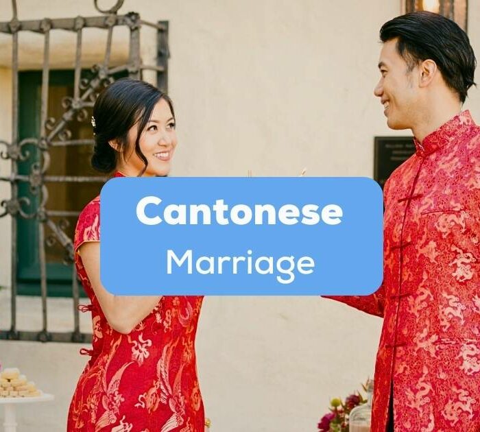 A photo of a newly wed Asian couple wearing their traditional red clothes behind the Cantonese Marriage texts.