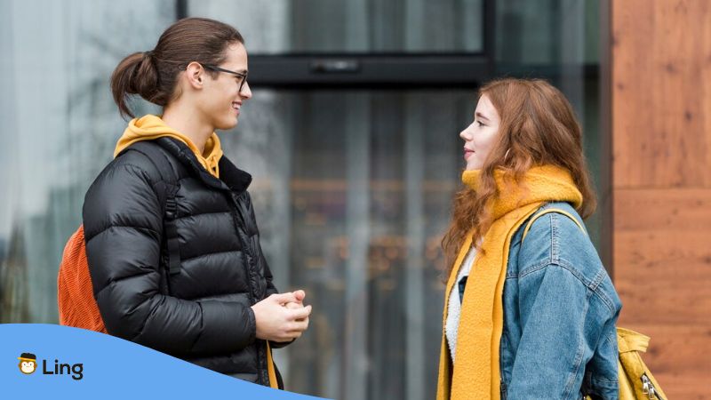 A photo of a young male and female from different parts of Lithuania talking outside wearing winter clothes.