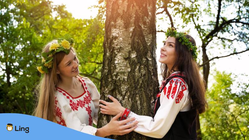 A photo of two friendly Lithuanian women hugging a tree.