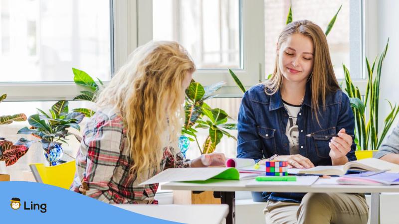 A photo of two women studying inside their classroom, one of the characteristics of Lithuanian people.