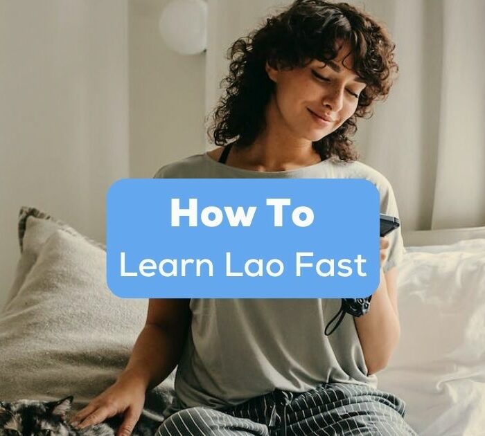 A photo of a female language learner using her phone sitting on a bed with her cat behind the How To Learn Lao Fast texts.