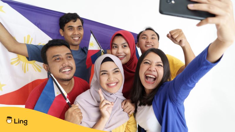 filipinos posing for a selfie while holding big and small philippine flags