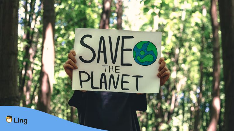 A photo of a man holding a poster with save the planet text on it.