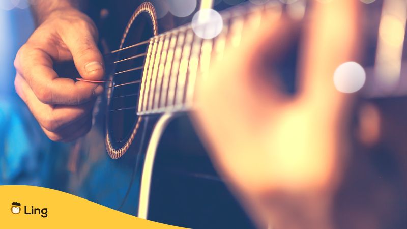 hands of a music artist using a pluck in playing a guitar