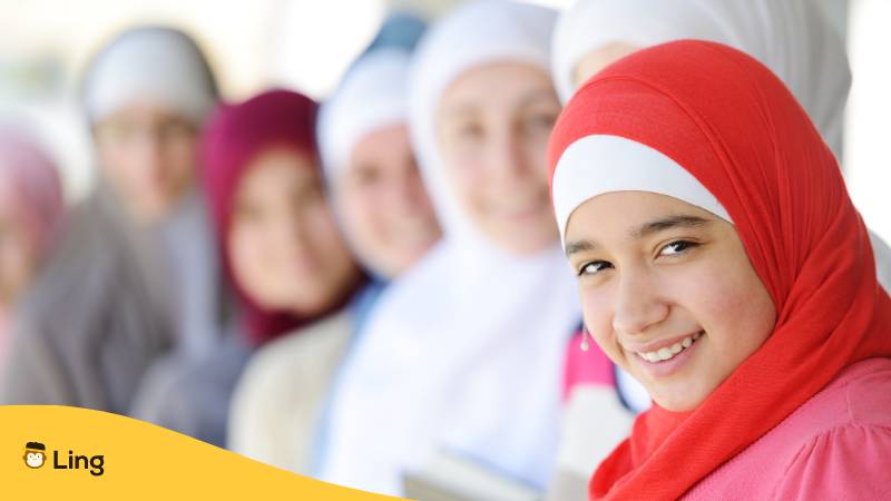 Arabisches Mädchen lächelt freundlich, im Hintergrund sind weitere arabische Mädchen unscharf zu sehen. Finde arabische Namen für deine Tochter mit der Ling-App