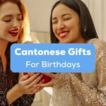 A photo of two pretty young interracial ladies in dresses happily unpacks a red gift box indoors behind the Cantonese Gifts For Birthdays texts.