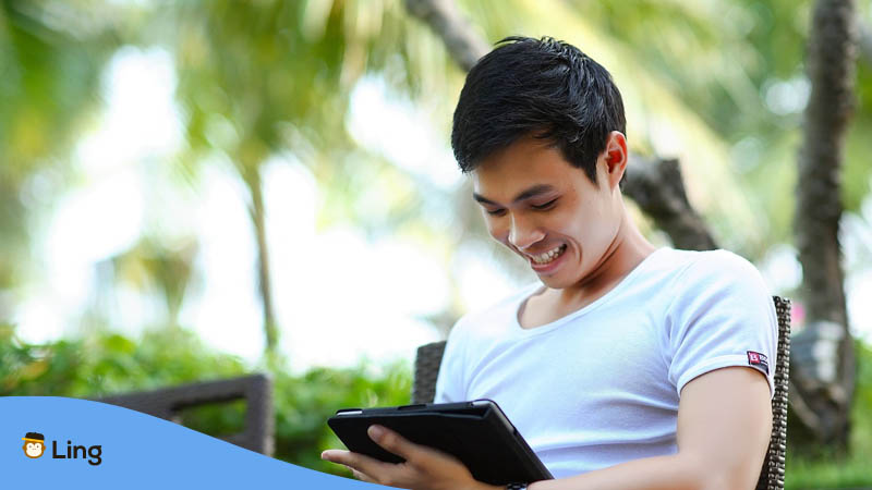 Asian man smiling with a tablet
