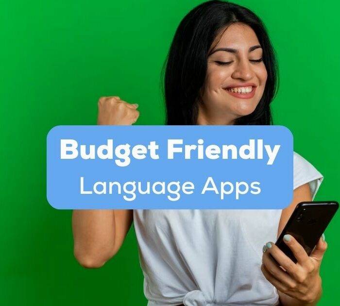 A photo of a smiling young Caucasian woman with a closed fist looking at her phone behind the Budget Friendly Language Apps texts.
