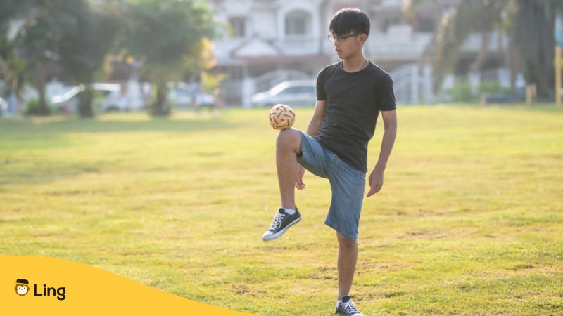 boy wearing black shirt playing sepak takraw in an open field