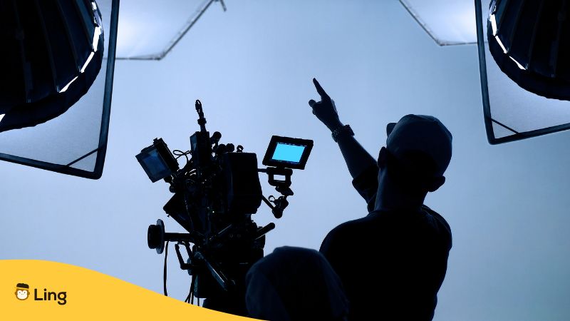 silhouette of a director behind a camera in a studio with lights set up