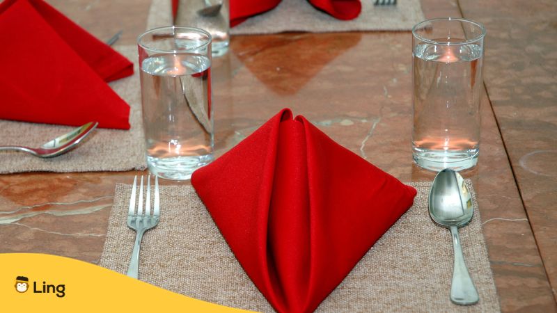 red table napkins, spoon, fork, and glasses of water arranged in a dining table