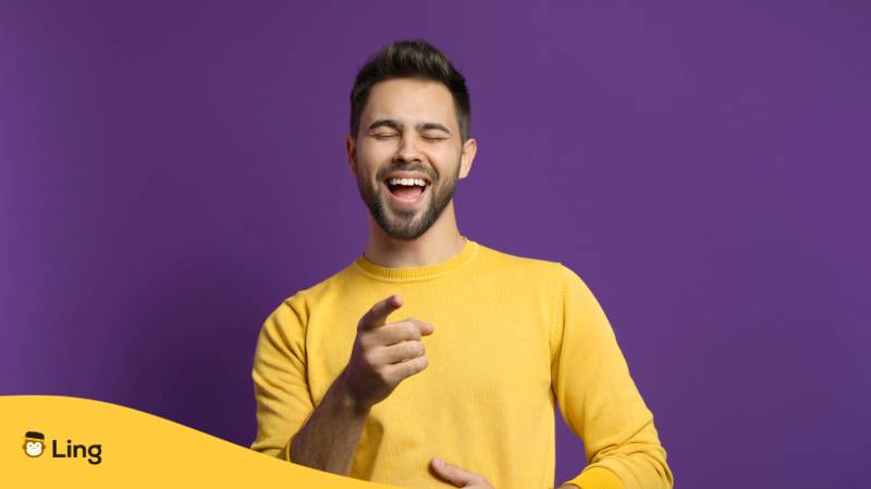 Brünetter Mann lacht laut, weil er mit der Ling-App lustige italienische Redewendungen entdeckt hat