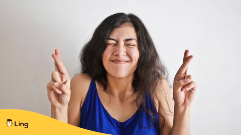 Junge Frau benutzt einen lockeren Ausdruck, um viel Glück auf Bulgarisch zu sagen, und überkreuzt ihre Finger