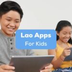 A photo of two happy young language learners using their tablets while sitting on a couch behind the Lao Apps For Kids texts.