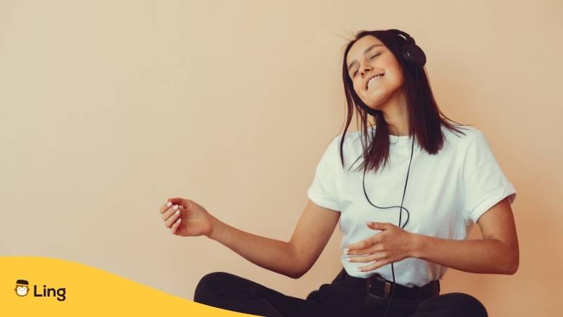 Junge dunkelhaarige Frau hört sich litauische Lieder über Kopfhörer an, die sie mit der Ling-App entdeckt hat