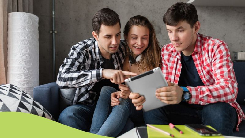 best apps for learning Lithuanian - A photo of three sitting friends studying Lithuanian using their tablet