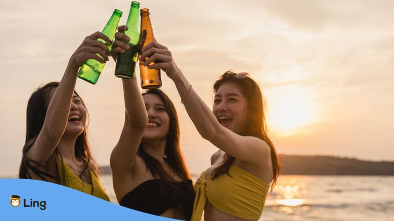 A photo of a group of Asian teenage girls who know how to order beer in Thai and are celebrating at a beach party.