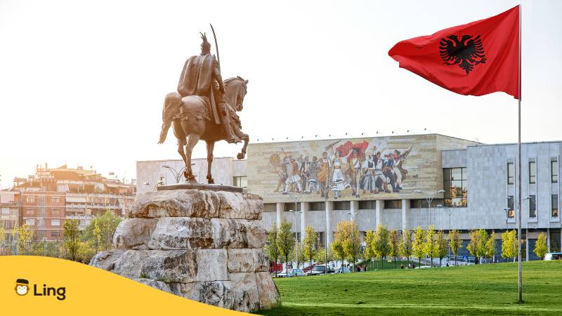 Albanische Flagge und Statue vor albanischen Nationalmuseum. Erfahre mit der Ling-App, Ist Albanisch schwer zu lernen?