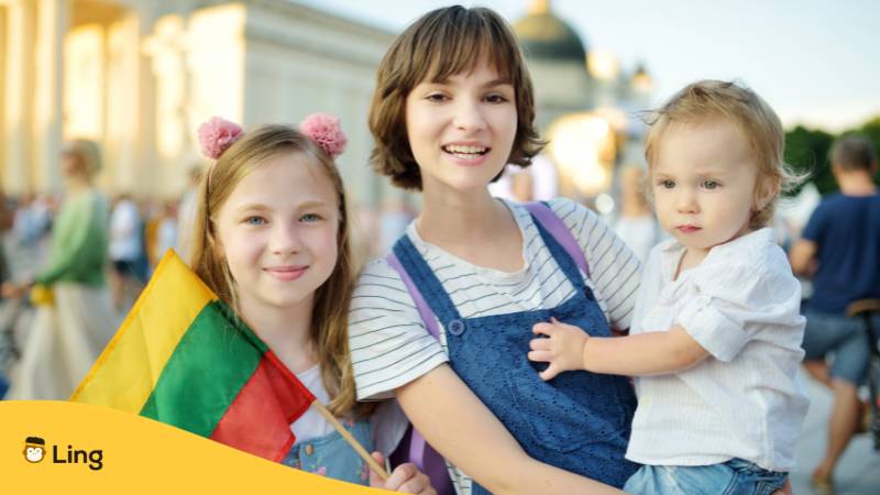 Eine litauische Mutter und ihre beiden Kinder. Die größere Tochter trägt die litauische Flagge zur Feier der Krönung des Mindaugas, sie feiern litauische Traditionen