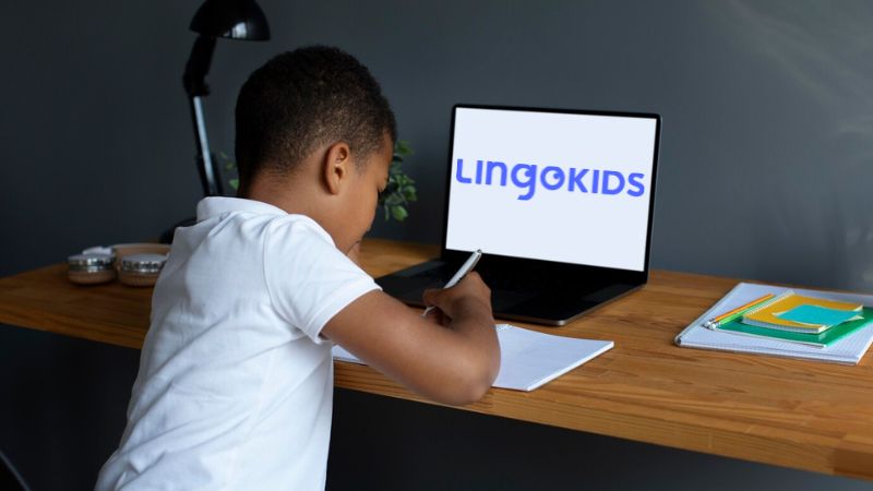 Lingokids review - A photo of a learning boy writing in front of a laptop