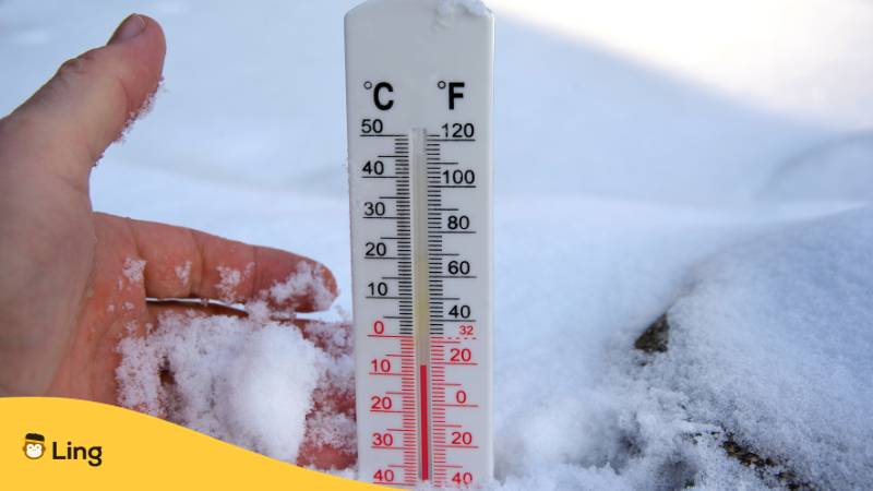Ein Mann hält Thermometer in der Hand im Schnee. Lerne mit der Ling-App, was Wetter auf Slowakisch bedeutet.