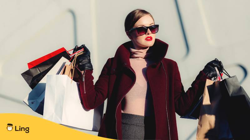 Frau mit Sonnenbrille und Mantel hält Einkaufstaschen. Lerne grundlegende slowakische Fragewörter mit der Ling-App.

