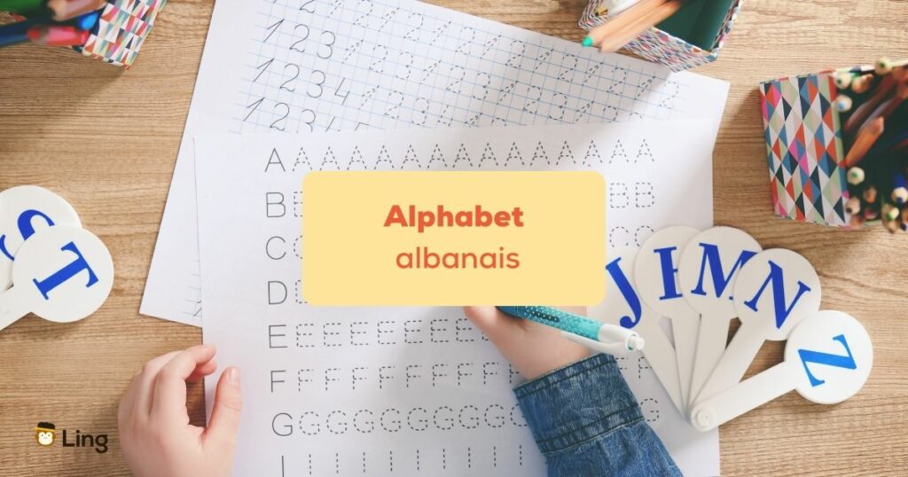 alphabet albanais Main écrivant l'alphabet sur une feuille blanche avec un stylo bleu
