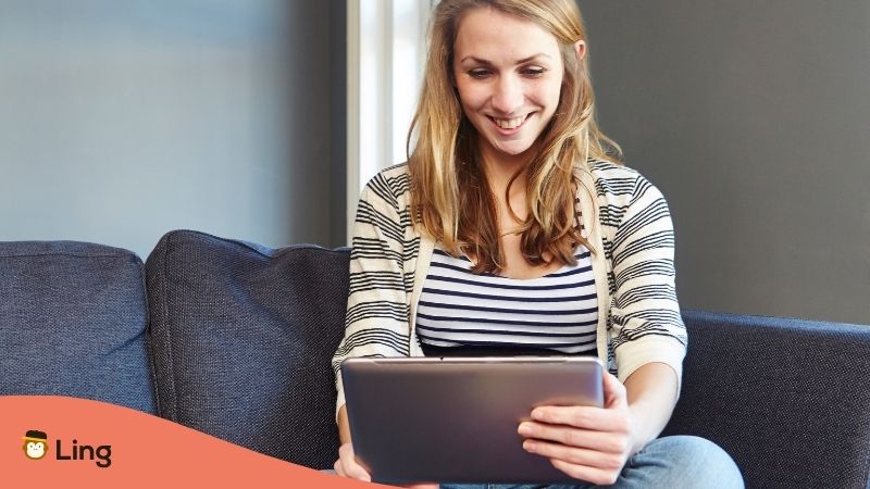 A Woman Using A Tablet To Learn Languages On Her Couch